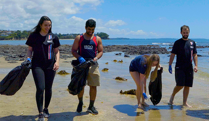 graduates doing a beach clean up in BDO tshirts