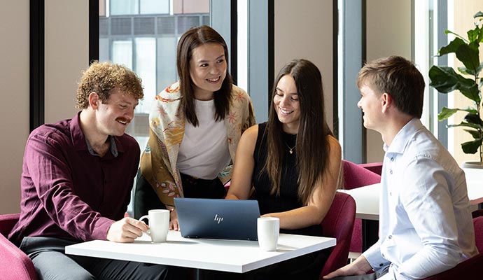 Group of students meeting and looking at laptop
